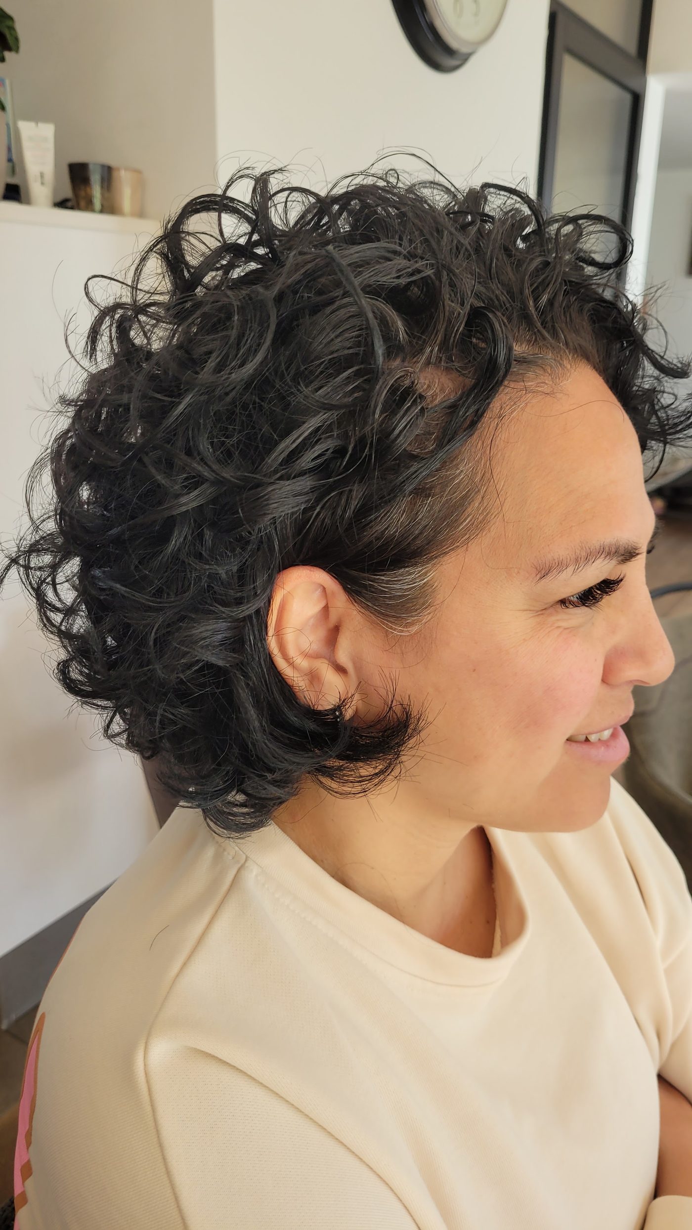 Vrouw met kort, donker krullend haar, van opzij