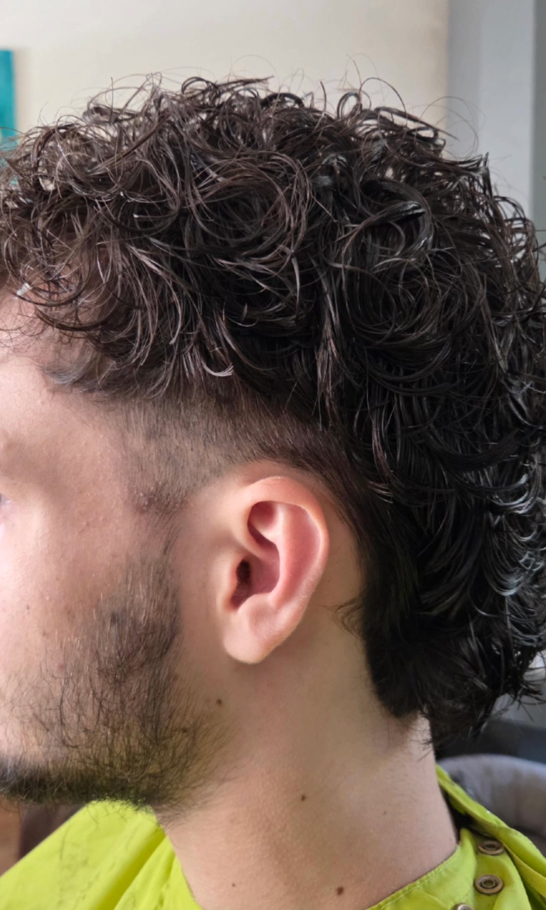 Jongeman met een permanent: krullen boven op het hoofd, kort aan de zijkant